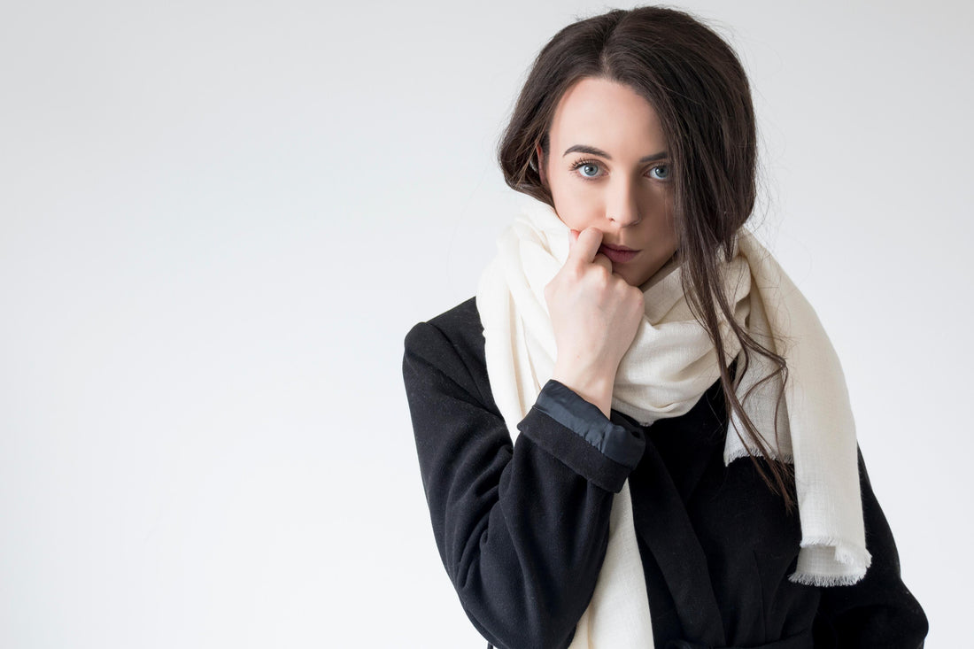 Woman in a black coat wearing a cream cashmere scarf