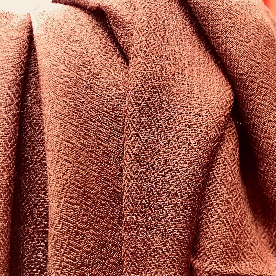 Image shows the folds of a coffee brown cashmere scarf showing the diamond weave pattern and lustre